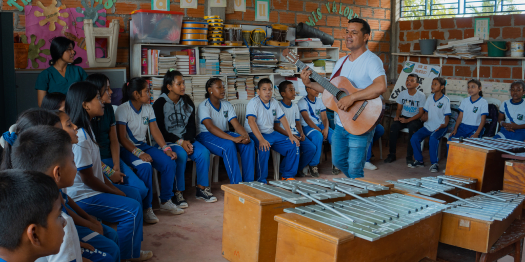 Teacher playing music with children and adolescents in Colombia under the project Voices of Reconciliation