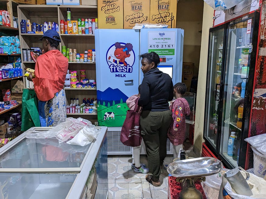 A woman with her child buying milk from a FRESH Point inside a small supermarket