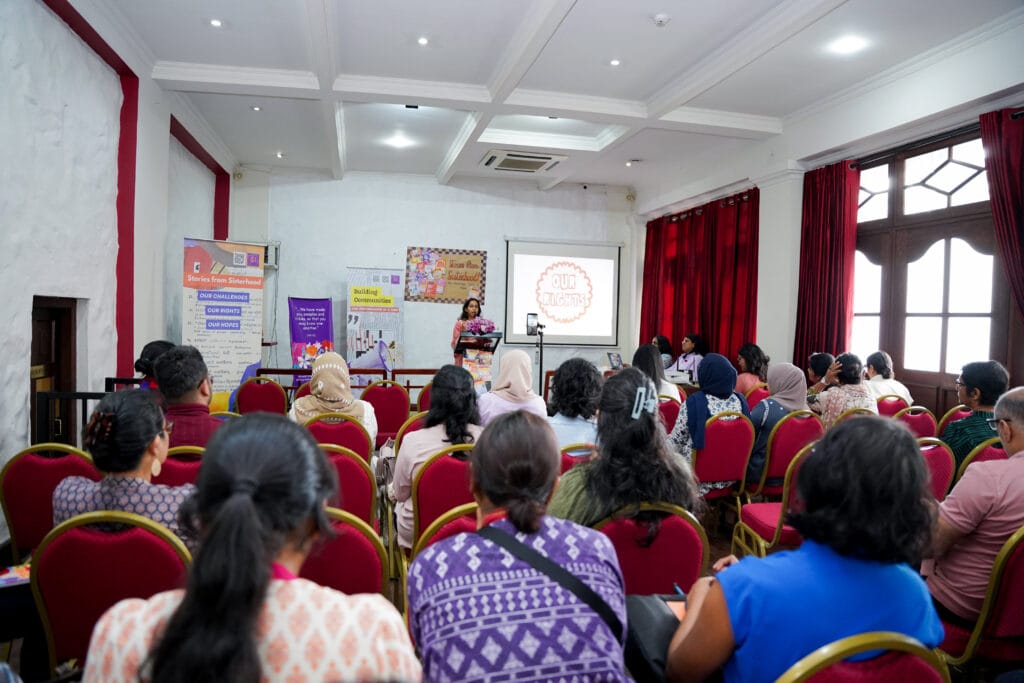 A room of women watching Nabeela speaking on stage